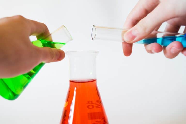 beakers with colored liquids being poured together to form a reaction