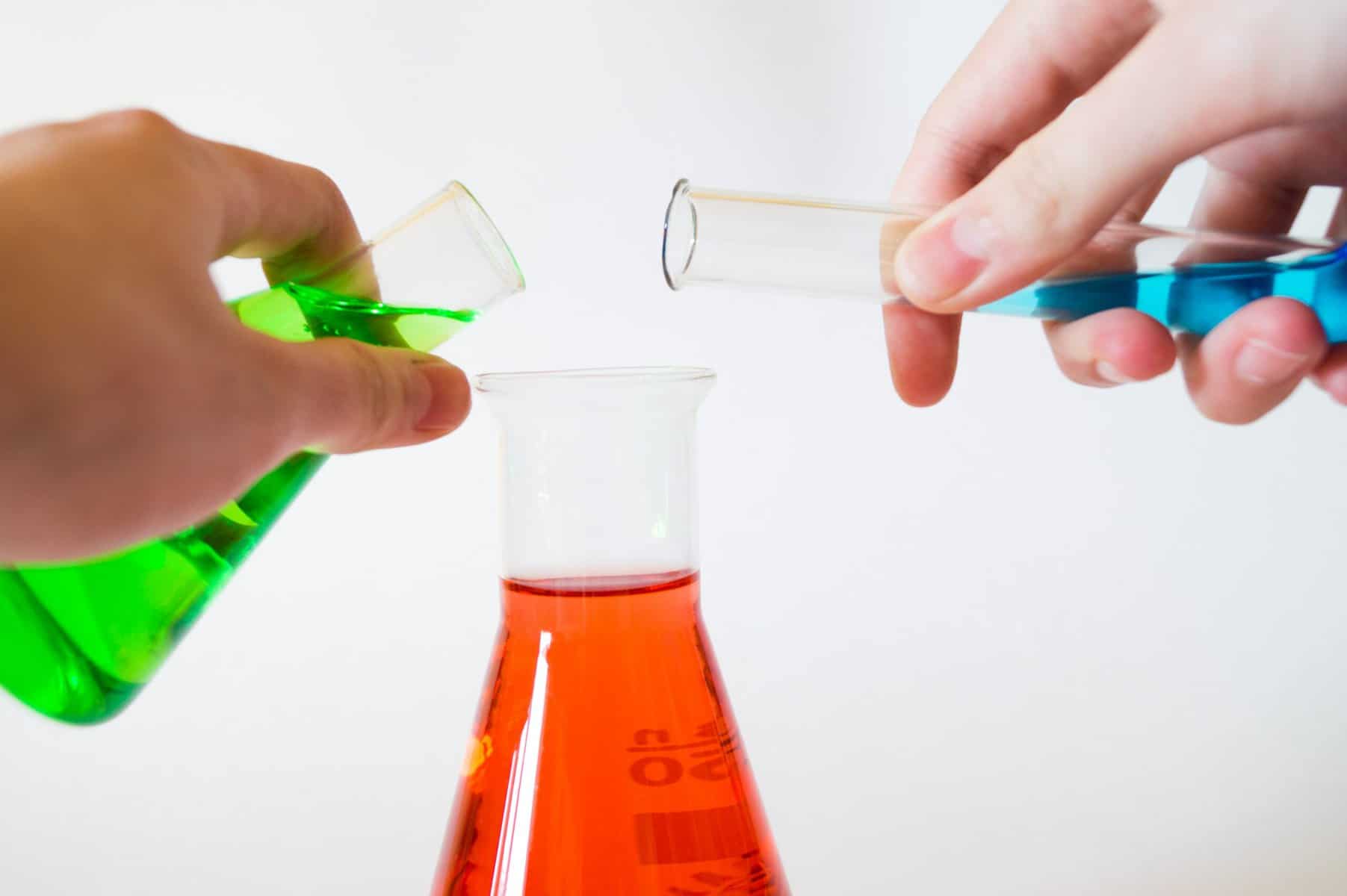 beakers with colored liquids being poured together to form a reaction