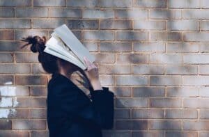 girls with book over her face - overwhelmed with study